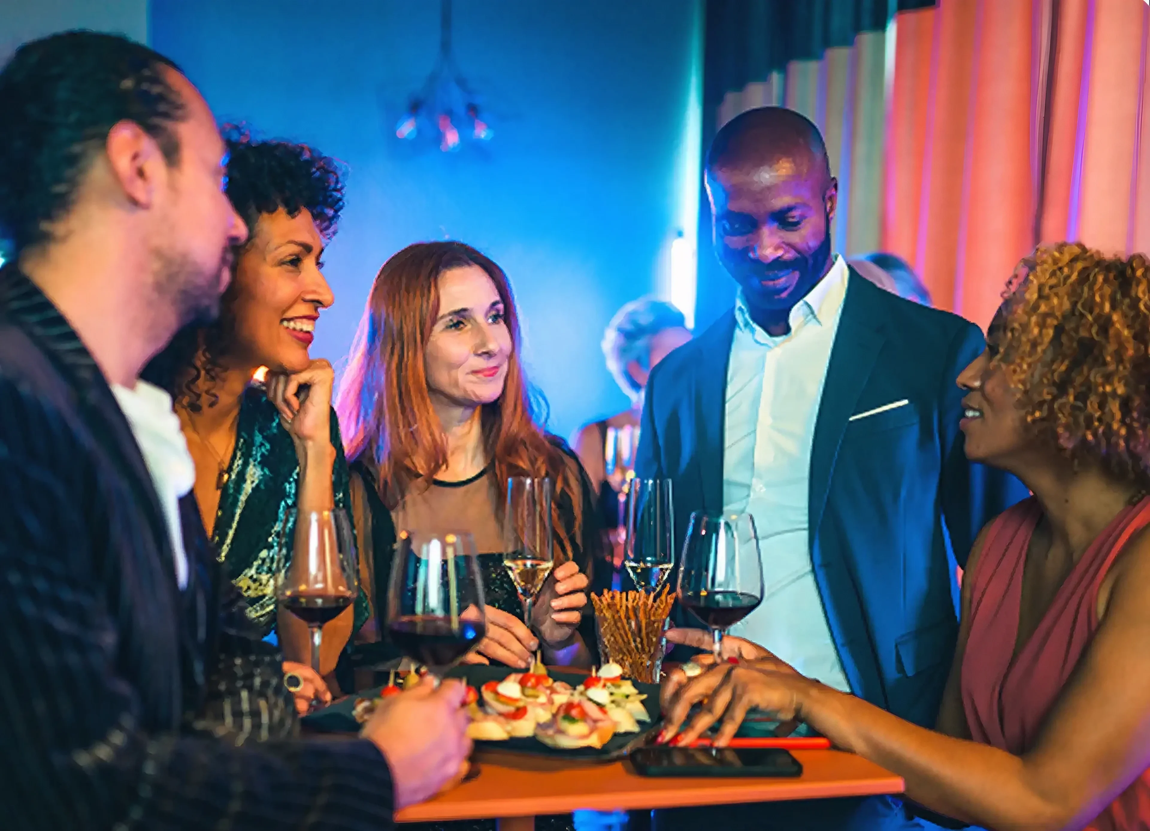 Group of friends enjoying drinks and appetizers at a lively bar.